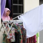 a Malaysian Woman Puts Away a White Flag After She Received Help from Others.(reuters: Lim Huey Teng)