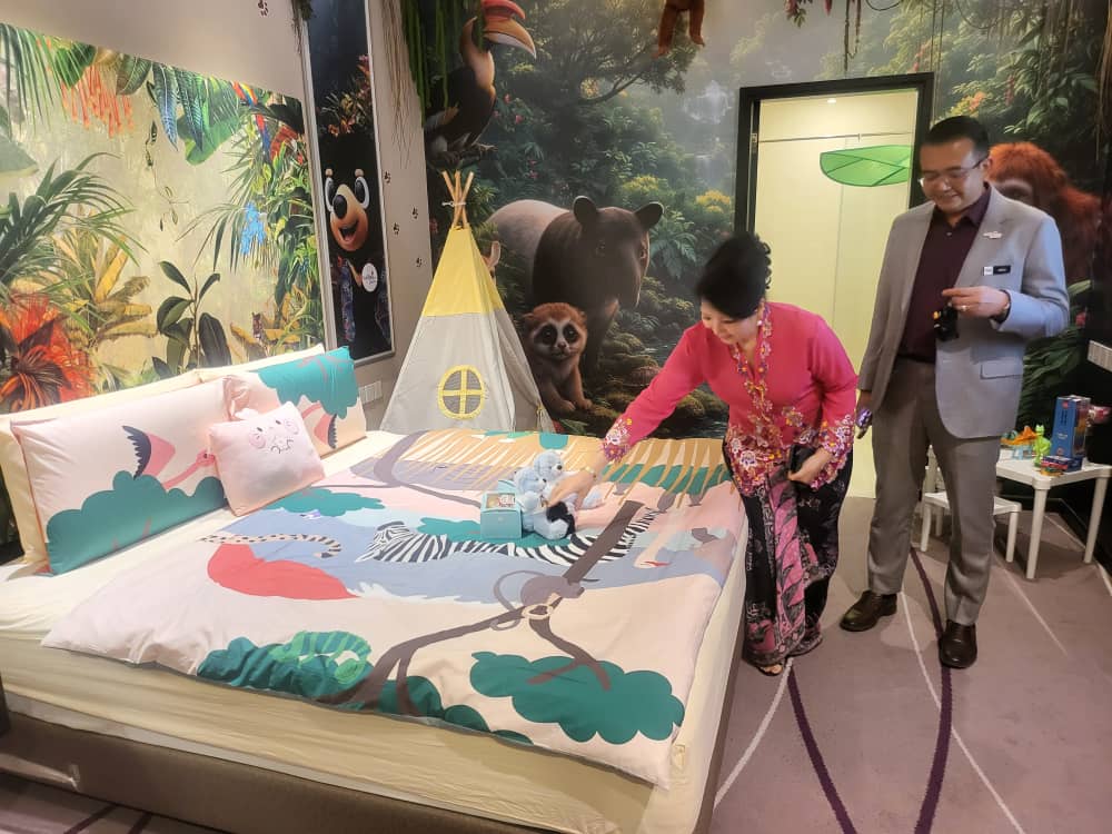 the Specially Designed Room Includes Themed Bedding, Plush Mascots, a Children's play tent and family-friendly amenities aimed at encouraging domestic tourism and staycations. Dorsett's Datin Jasmine touches a plush toy while Amirul of Tourism Malaysia looks on.